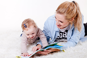 Mom and Baby Laying on Floor Reading Book with Life Insurance in New Rochelle